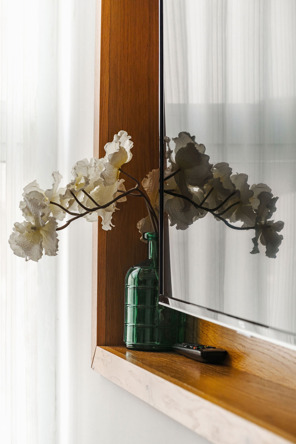 Vase vert et fleurs blanches devant le miroir à l'Hotel Kikar Netanya