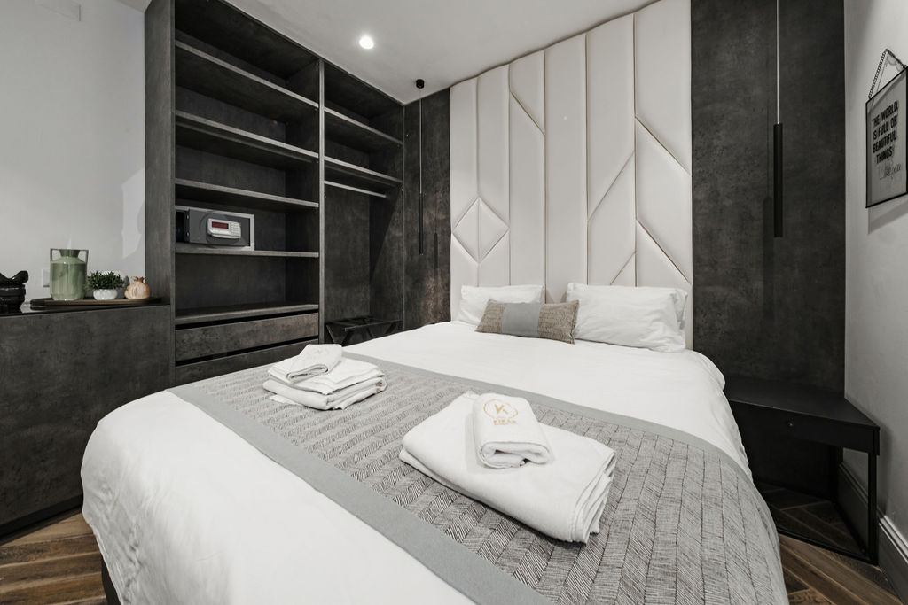 Chambre King avec coffre-fort, étagères et tête de lit capitonnée à l'Hotel Kikar Netanya