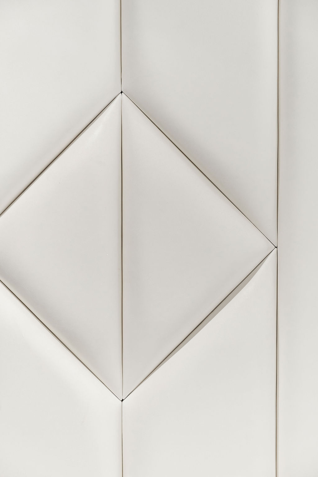 Détail losange d'une tête de lit en cuir blanc capitonné