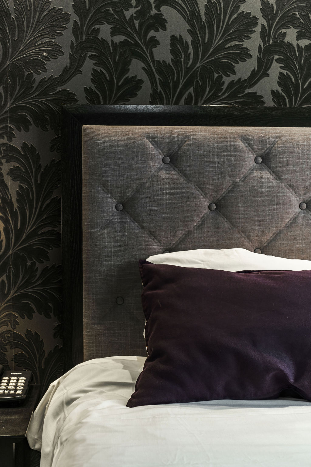 Détail de tête de lit capitonnée et coussin violet à l'Hotel Kikar Netanya