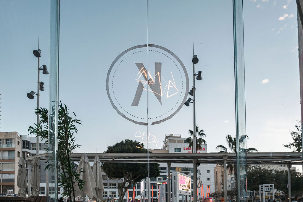 Logo Kikar Boutique Hotel gravé sur la vitrine donnant sur la place