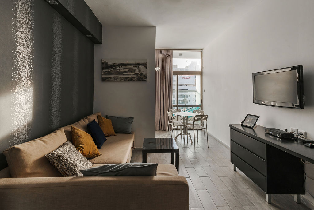 Salon spacieux d'une suite avec téléviseur et balcon ouvert à l'Hotel Kikar Netanya