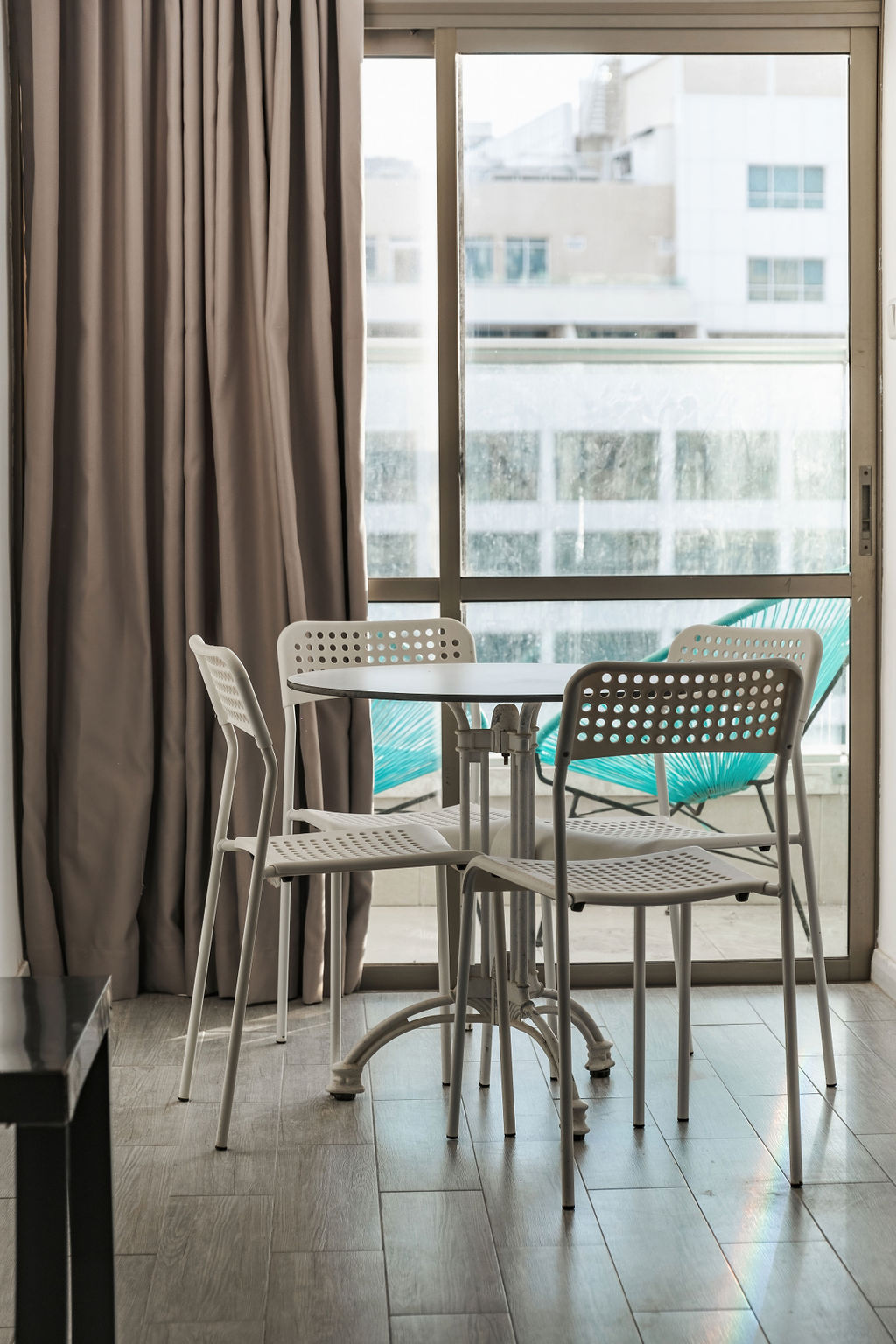 Coin repas sur balcon avec fauteuils turquoise et vue sur Netanya