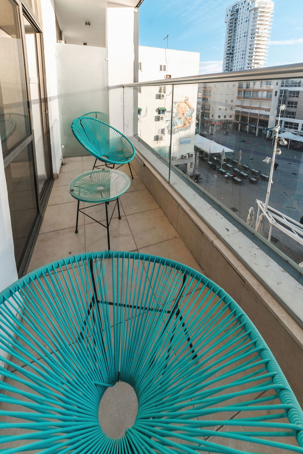 Balcon privé avec fauteuils turquoise donnant sur la place de Netanya