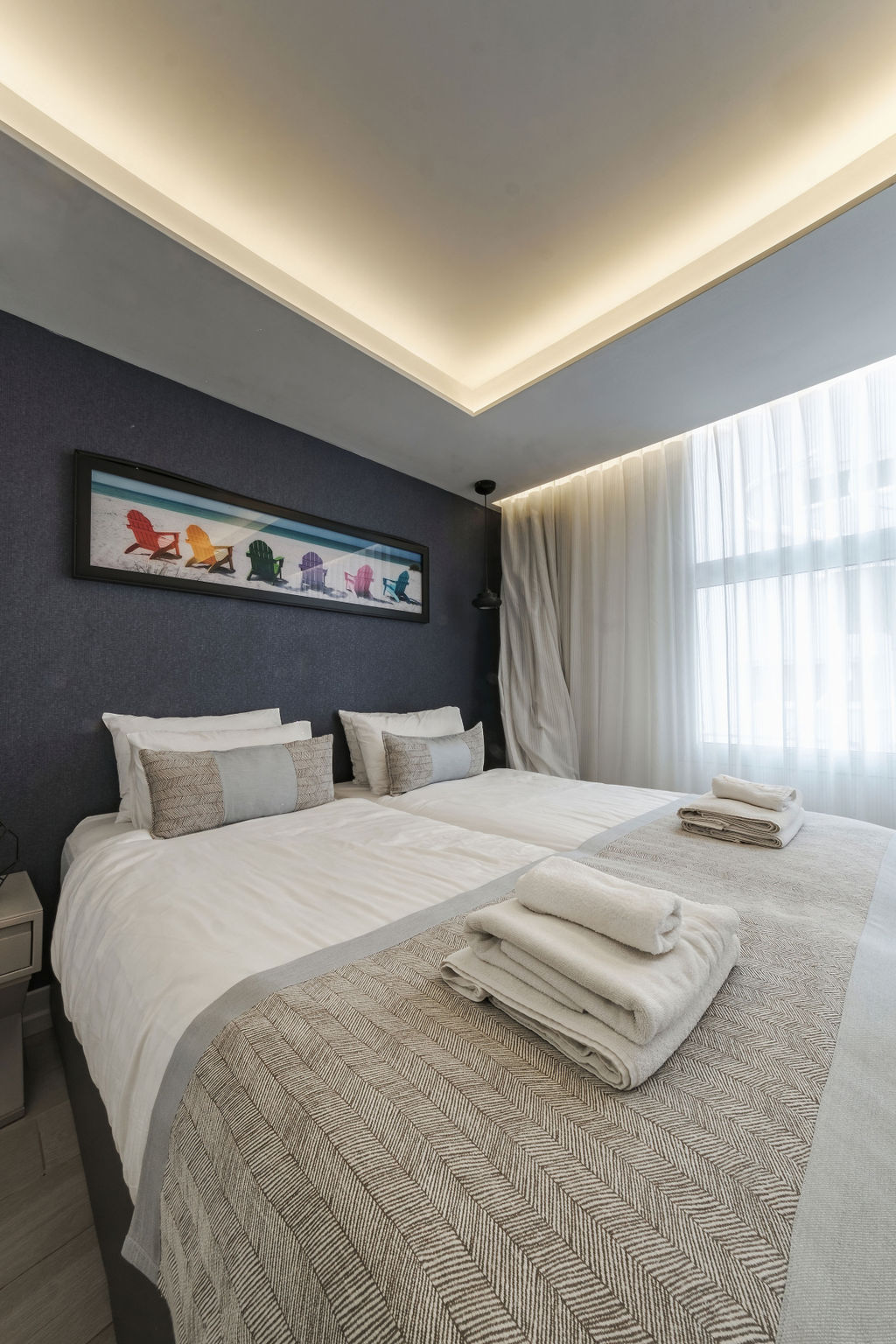 Chambre Deluxe avec lits jumeaux et œuvre chaises de plage à l'Hotel Kikar Netanya