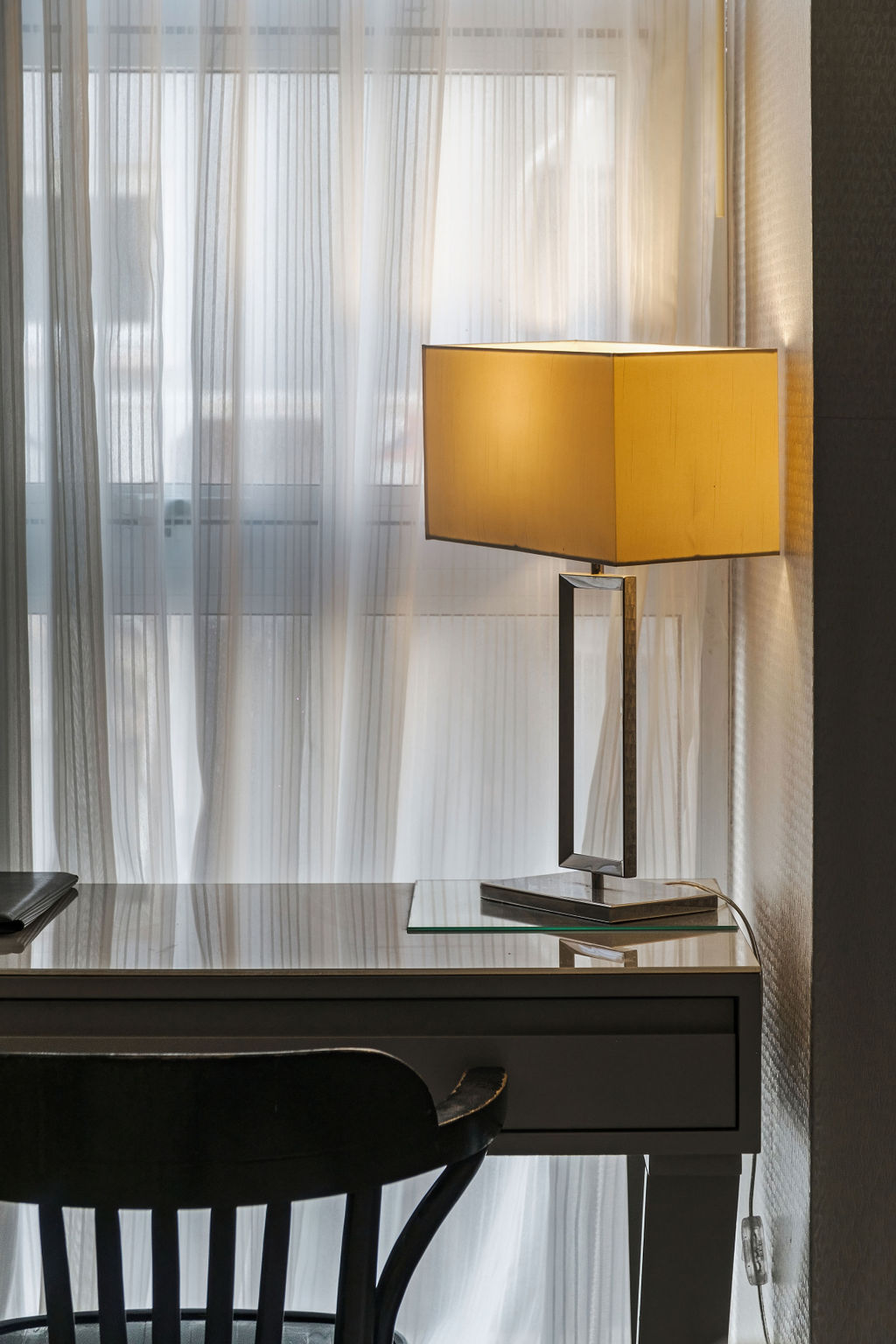 Lampe de bureau dorée devant rideau voilage à l'Hotel Kikar Netanya