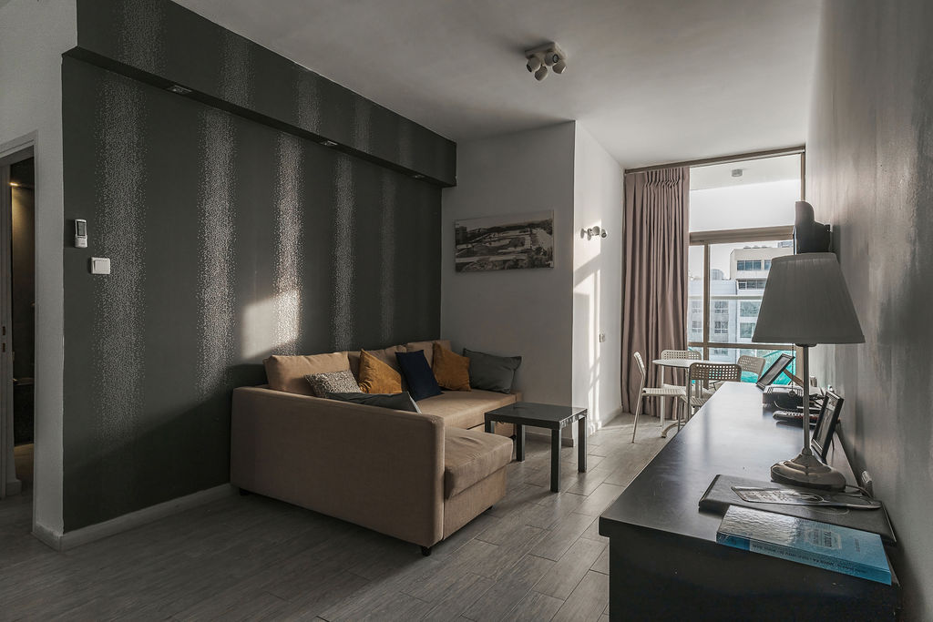 Suite avec salon, canapé et accès au balcon à l'Hotel Kikar Netanya