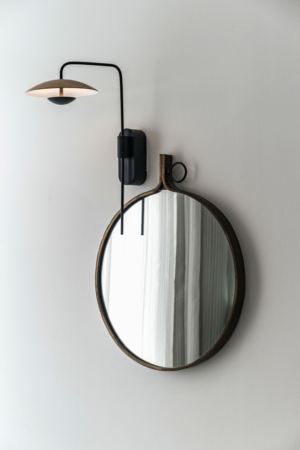 Applique en bois et miroir rond en laiton dans une chambre de l'Hotel Kikar Netanya