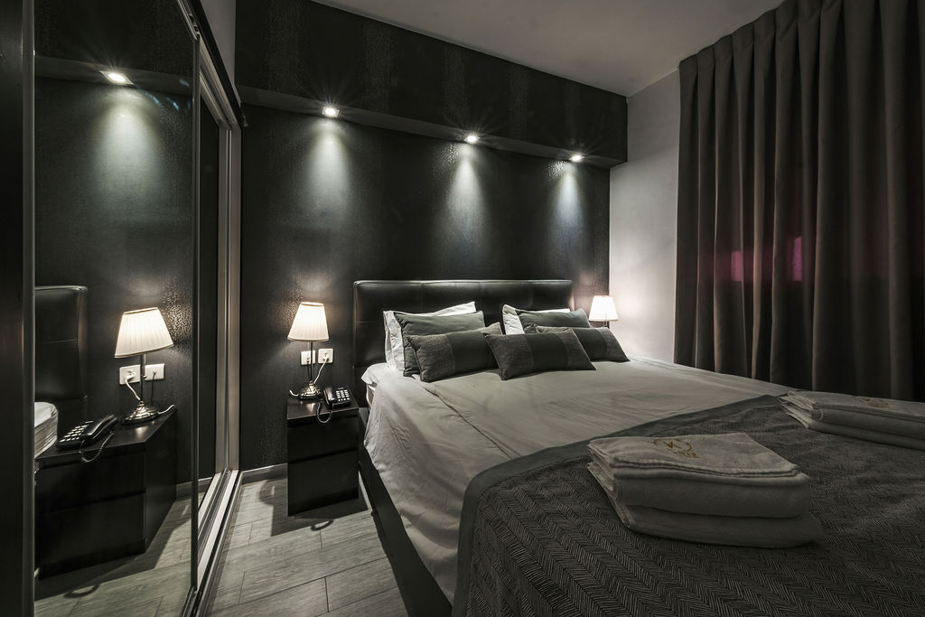 Chambre King intimiste aux murs noirs et tête de lit en cuir