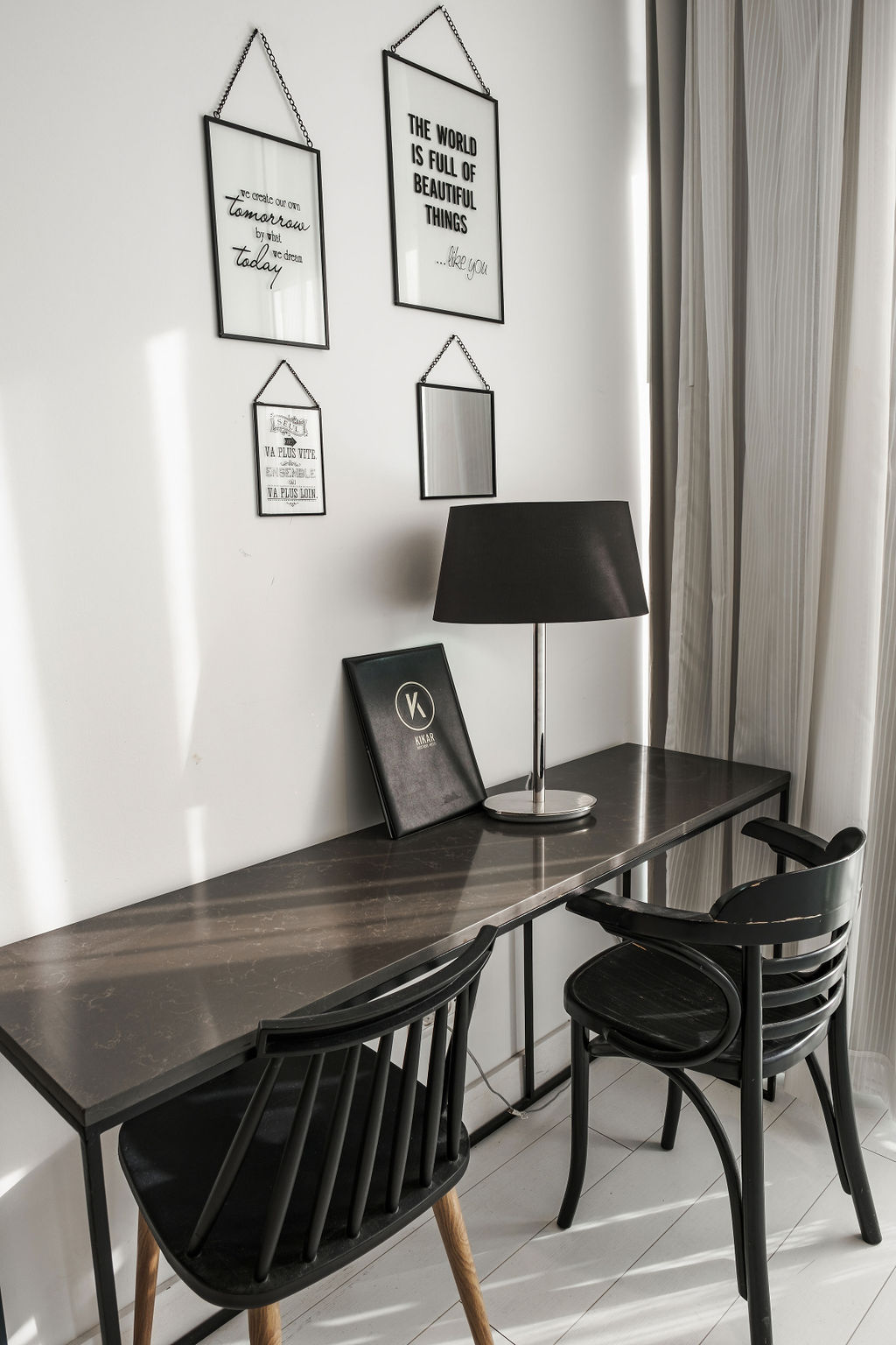 Coin bureau avec citations encadrées, lampe et chaises bistrot noires