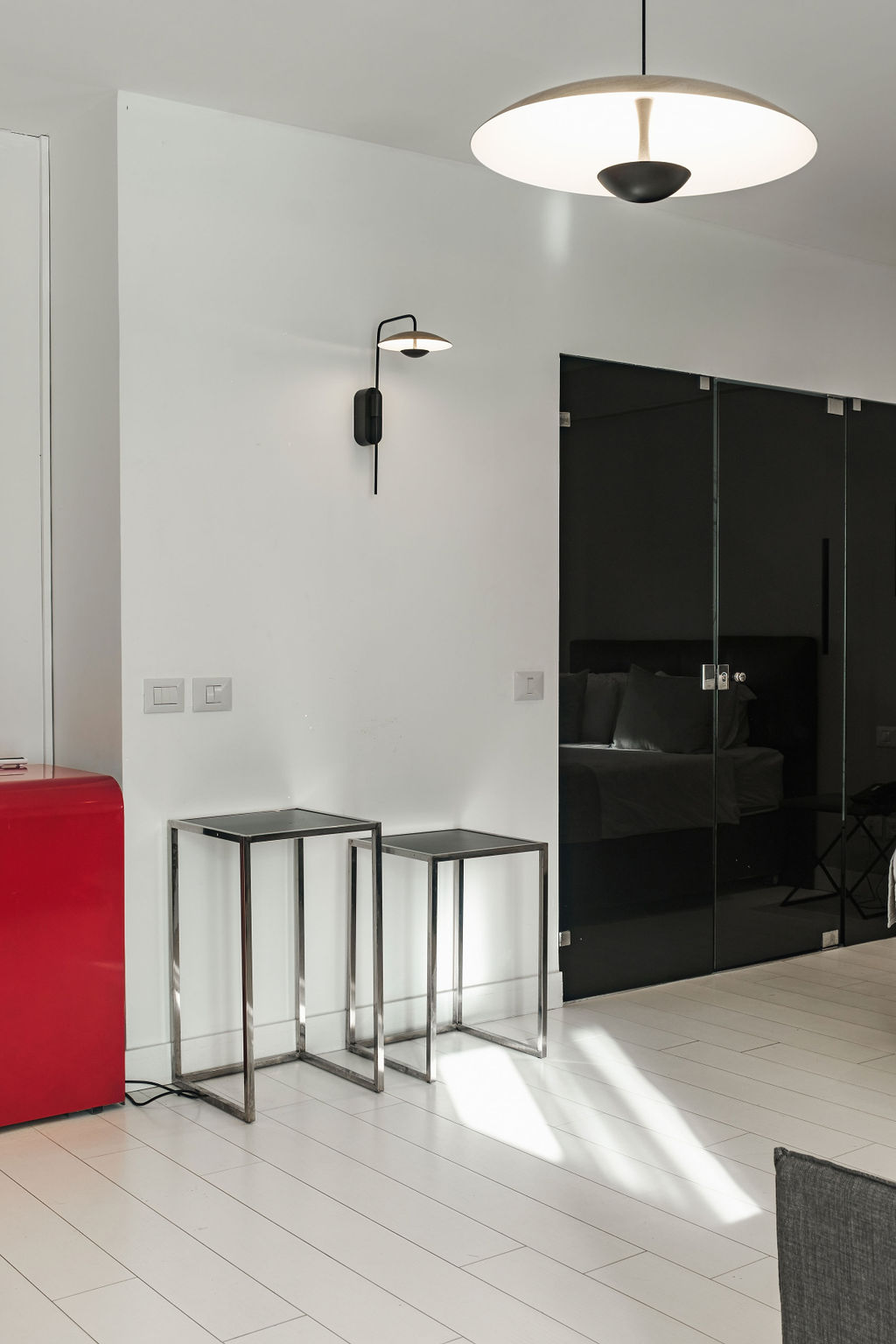 Salon ouvert avec mini-frigo rouge et chambre vitrée noire à l'Hotel Kikar Netanya