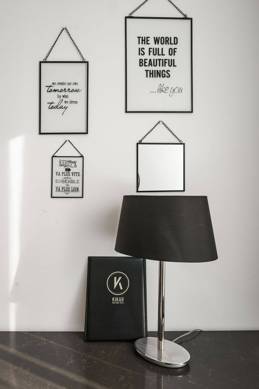 Mur de citations encadrées avec menu Kikar Boutique Hotel et lampe noire